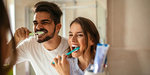 Man and woman with dental implants in Flower Mound, TX brushing their teeth