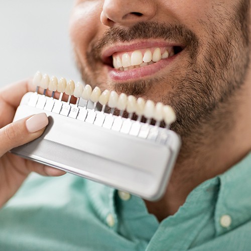 Man smiling while dentist determines shade of teeth