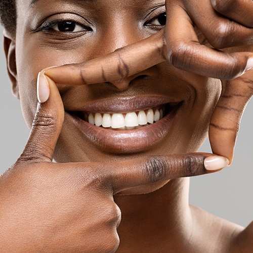 Smiling woman framing her white teeth with her fingers