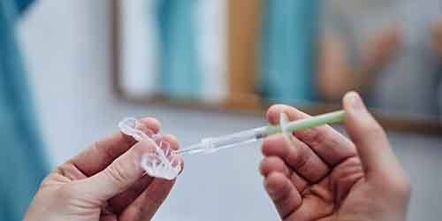 Someone injecting whitening gel into a dental tray