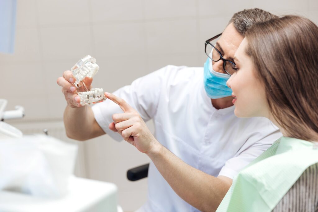 Dentist showing smiling patient model of teeth